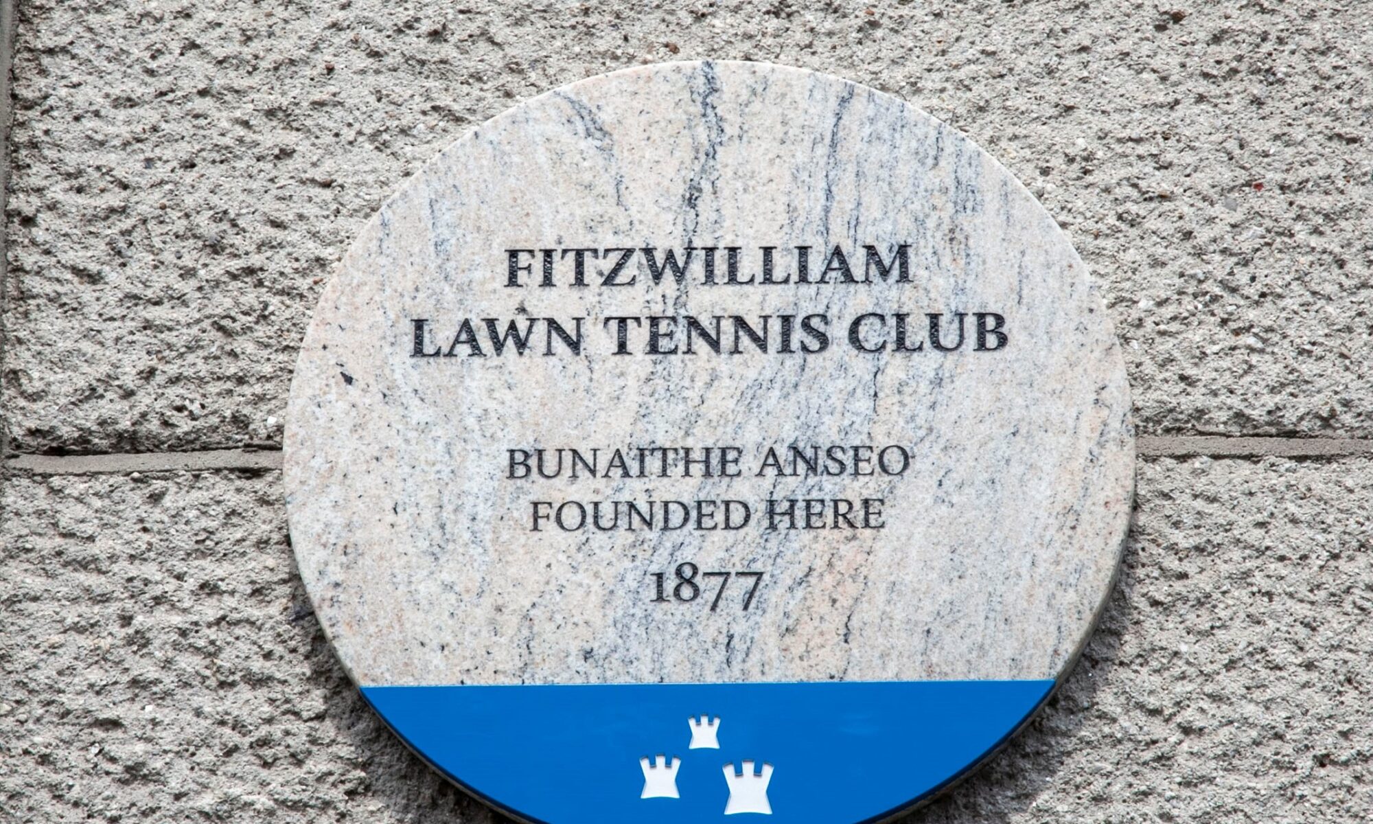 Photograph of a Dublin City Council commemorative plaque. The text on the plaque reads 'Fitzwilliam Lawn Tennis Club bunaithe anseo founded here 1877'.
