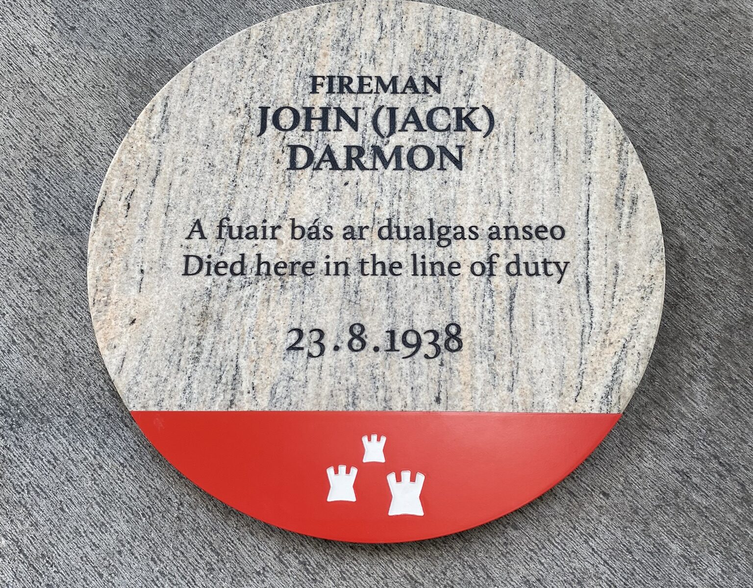 Photograph of a commemorative plaque with black text on grey granite with the Dublin City Council logo at the bottom in white on a red background.